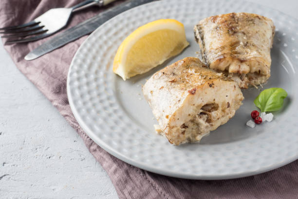 baked pollock fish with lemon and spices on a plate napkin on the table - pollock trawler imagens e fotografias de stock