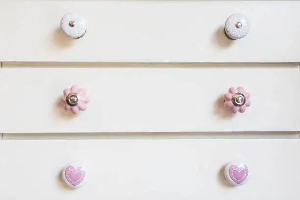 Photo of White closet doors with colorful knobs close-up