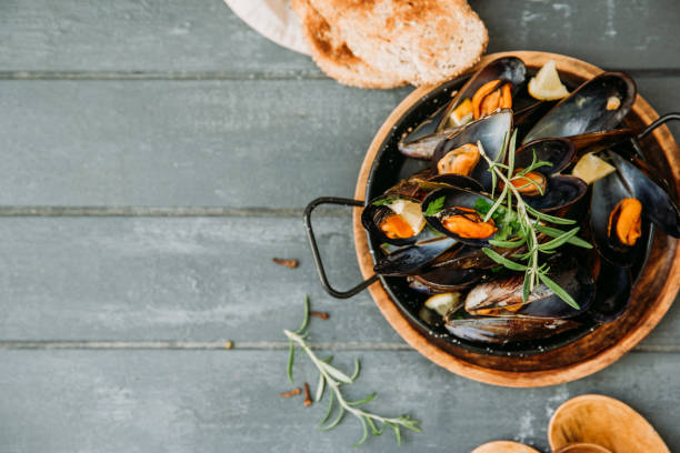 istock Shellfish Mussels with lemon and herbs on wooden background. Top view. 953597856