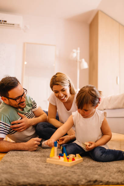 istock Cute little girl is having fun while she is solving puzzles on the floor in bedroom with her parents 953601062
