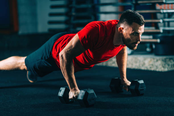 クロス トレーニング。ダンベルと腕立て伏せをやって若い男 - weightlifting crossfit weight training men ストックフォトと画像