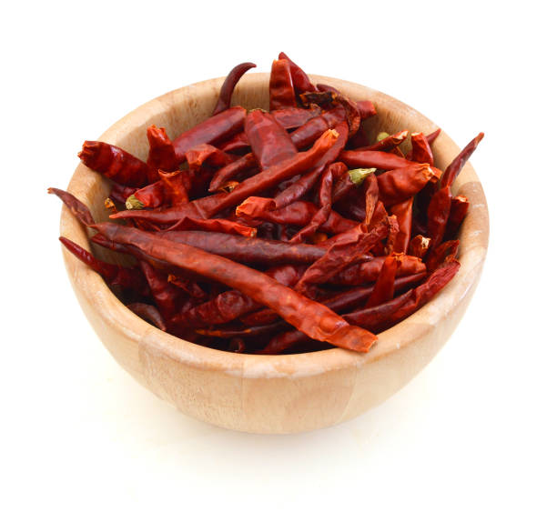 сухой красный перец в деревянной миске на белом фоне - pepper spice dried plant image стоковые фото и изображения