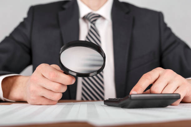 istock Businessman holding magnifying glass zoom and looking to documents 953619630
