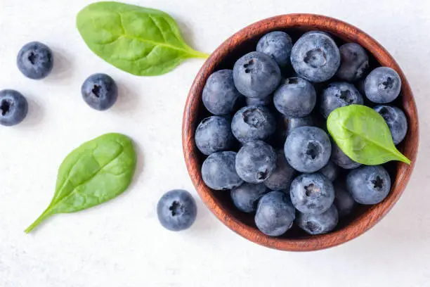 Photo of Fresh blueberries in bowl on white background, top view