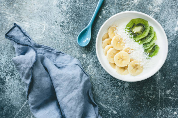 Yogurt with banana, kiwi and coconut bowl. Vegan yogurt with fruits Yogurt with banana, kiwi and coconut bowl. Vegan yogurt with fruits. Healthy eating, dieting, fitness, healthy lifestyle concept. Table top view green apple slice overhead stock pictures, royalty-free photos & images