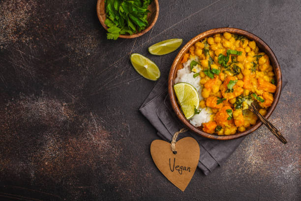 Vegan Sweet Potato Chickpea curry in wooden bowl on a dark background, top view. Healthy vegetarian food concept.