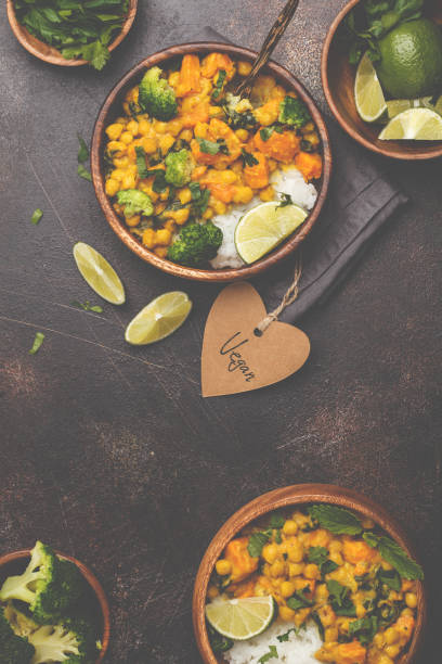 Vegan Sweet Potato Chickpea curry in wooden bowl on a dark background, top view. Healthy vegetarian food concept.