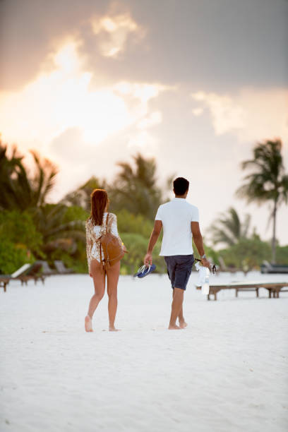istock Young Couple Enjoying Relaxing Walk on Sandy Beach 953637618