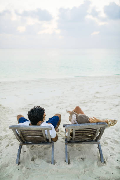 istock Adult Couple Relaxing on Deckchairs on Sandy Beach 953637640