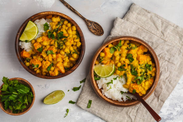 Vegan Sweet Potato Chickpea curry in wooden bowl on light background, top view, copy space. Healthy vegetarian food concept. Vegan Sweet Potato Chickpea curry in wooden bowl on a light background, top view, copy space. Healthy vegetarian food concept. chick pea stock pictures, royalty-free photos & images