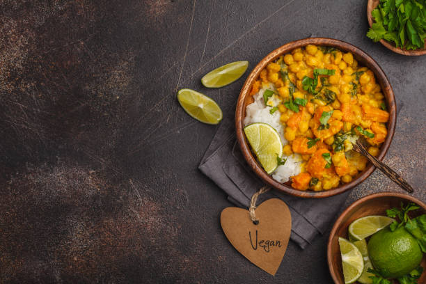 Vegan Sweet Potato Chickpea curry in wooden bowl on a dark background, top view. Healthy vegetarian food concept.