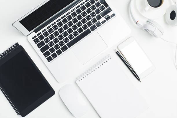 istock White desk top with devices and supplies 953643074