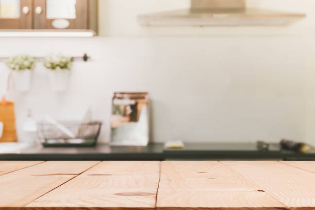 Wood table top island with blur modern kitchen room interior background