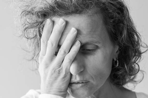 istock Middle aged woman with hand over face (black and white) 953650648
