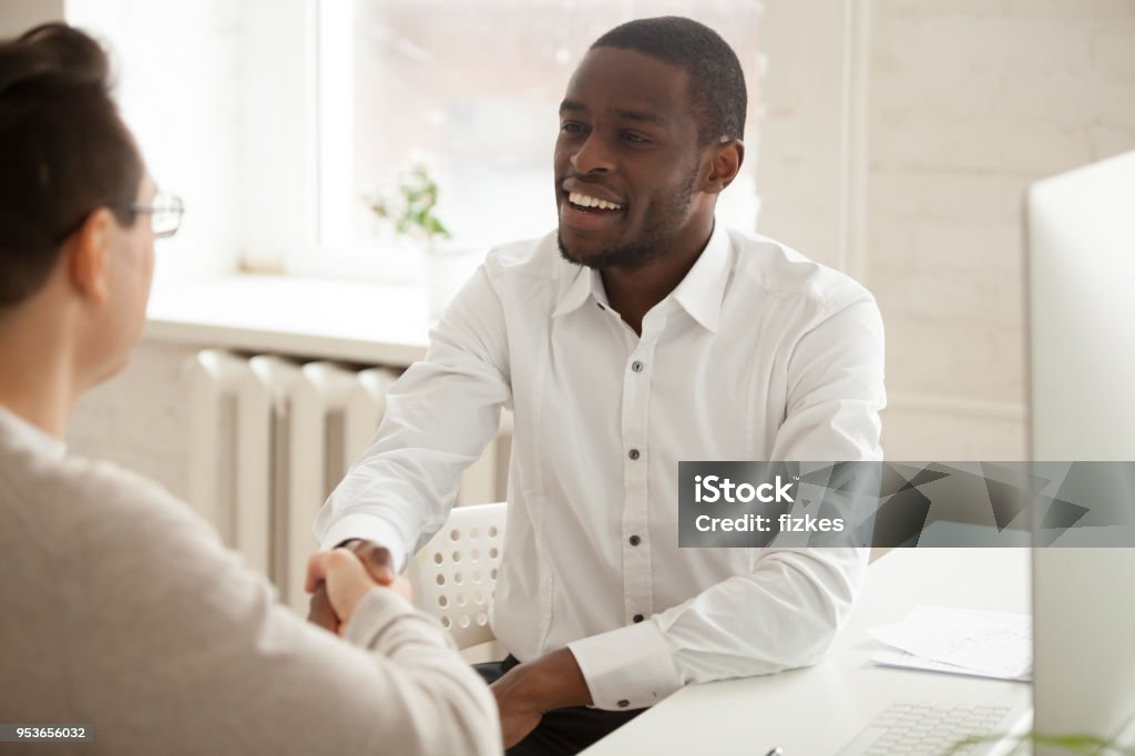 Sonriente hombre de negocios afroamericano atractivo apretón de manos nuevo socio en reunión - Foto de stock de Principios libre de derechos