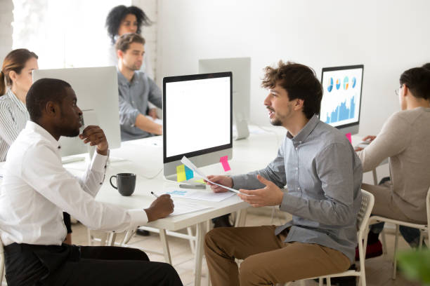 istock Young mentor teaching african new hire making notes in office 953656210