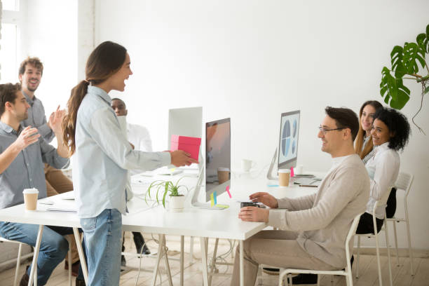 istock Colleagues congratulating excited coworker presenting birthday gift box in office 953656286