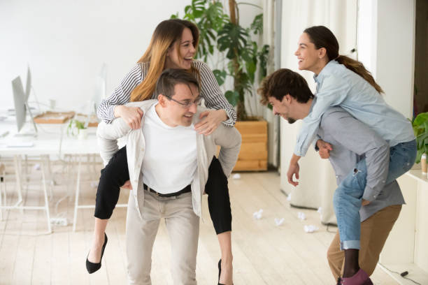 istock Happy colleagues having fun together enjoying piggyback ride in office 953656320