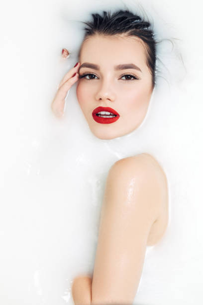 istock Attractive girl enjoys a bath with milk and roses 953656502