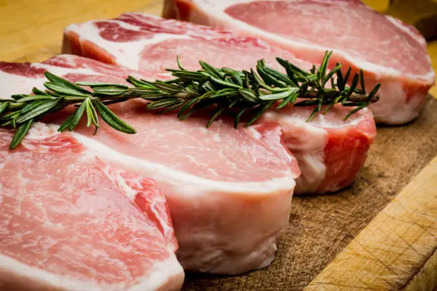 Thick raw pork chops ready to be grilled