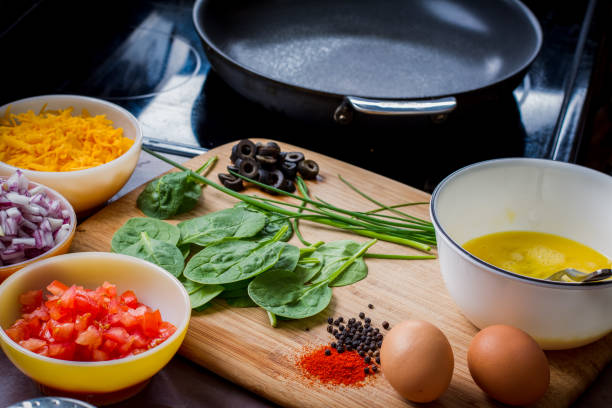 Making the Perfect Low Carb Omelette Eggs, cheese, spinach, onion, olives, tomato and seasoningson a bamboo cutting board,, the ingredients for a perfect ketogenic diet healthy breakfast. goodfood stock pictures, royalty-free photos & images