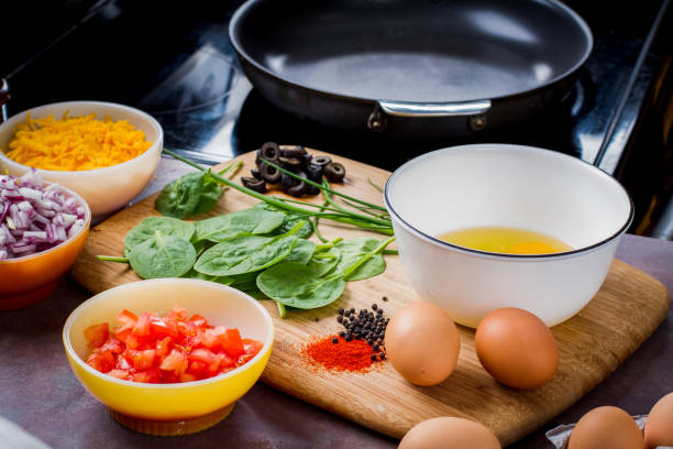 Making the Perfect Low Carb Omelette Eggs, cheese, spinach, onion, olives, tomato and seasoningson a bamboo cutting board,, the ingredients for a perfect ketogenic diet healthy breakfast. goodfood stock pictures, royalty-free photos & images
