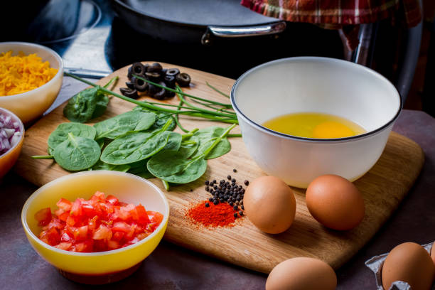 Making the Perfect Low Carb Omelette Eggs, cheese, spinach, onion, olives, tomato and seasoningson a bamboo cutting board,, the ingredients for a perfect ketogenic diet healthy breakfast. goodfood stock pictures, royalty-free photos & images