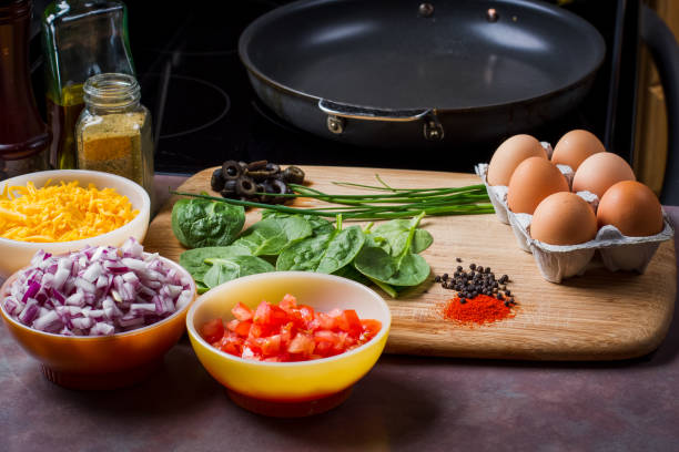 Making the Perfect Low Carb Omelette Eggs, cheese, spinach, onion, olives, tomato and seasoningson a bamboo cutting board,, the ingredients for a perfect ketogenic diet healthy breakfast. goodfood stock pictures, royalty-free photos & images