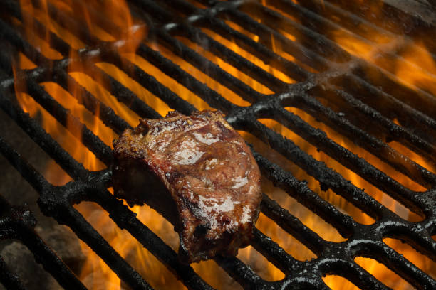 Low Carb, High Fat Lamb or Pork Chops on a Flaming Grill Delicious Grilled Lamb or Pork Chops, part of a ketogenic or low carb diet flaming on a grill goodfood stock pictures, royalty-free photos & images