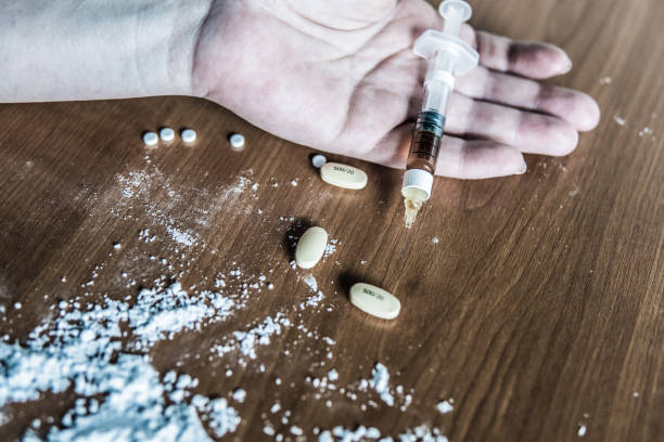 Hand of drug abuser on the floor with different drugs. stock photo