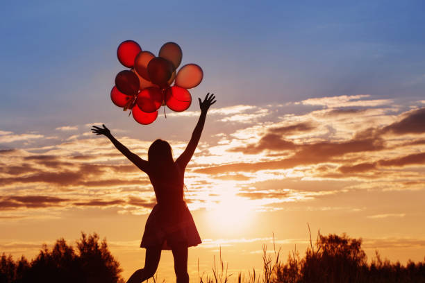 istock young women with balloons at sunset 953674314