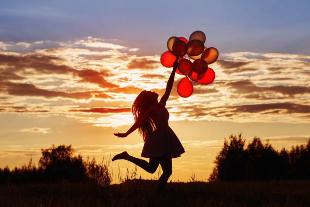 istock young women with balloons at sunset 953674324