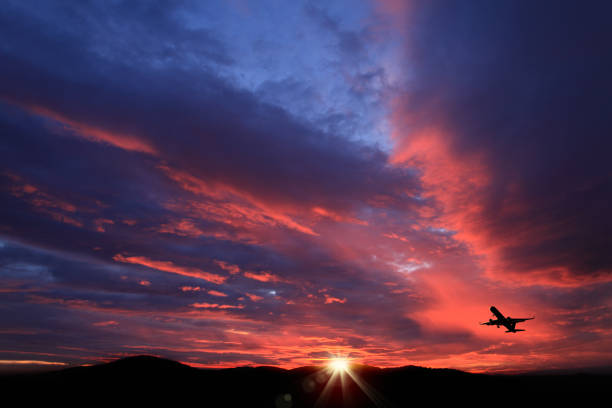 Transportation image of flying commercial passenger airplane over sunset sky