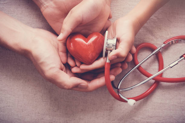 enfant et adulte tenant un coeur rouge avec stéthoscope, santé cardiaque, notion d’assurance maladie - cholestérol photos et images de collection