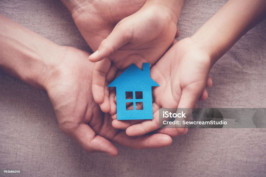 Adult and child hands holding paper house, family home and homeless shelter concept House Stock Photo