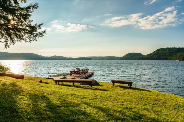 Waterfront with wooden chairs on dock, with watercraft and setting sun