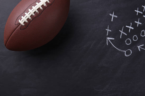American Football on Chalkboard Top view of an American style football on a chalkboard with a play diagramed. Horizontal format with copy space. american football game plan stock pictures, royalty-free photos & images