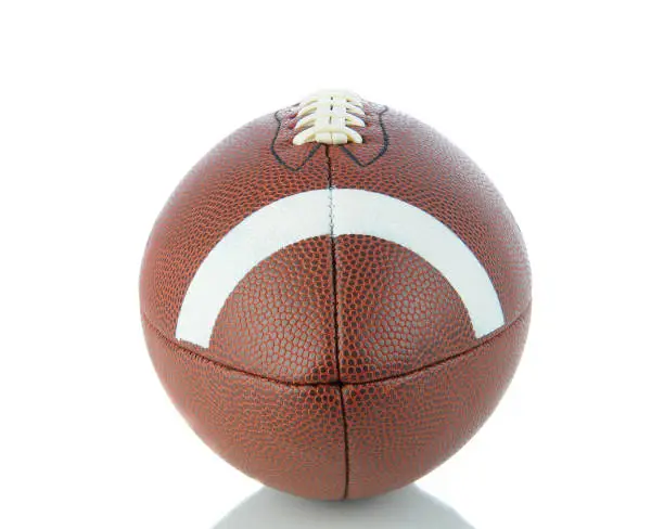 A closeup end view of an American Football on a white background with reflection.