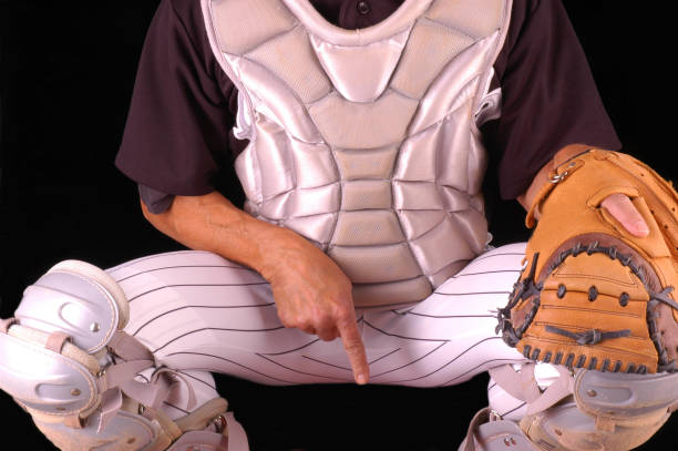 Baseball Catcher Giving Sing Baseball catcher in gear giving sign to pitcher, with black background. Man is unrecognizable. Chest Protector stock pictures, royalty-free photos & images