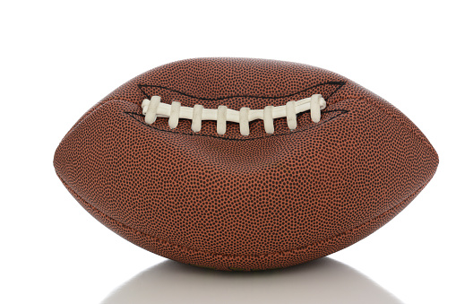 Closeup of an Professional American style football partially deflated on white with reflection.