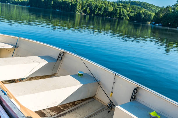 fishing rod with worms ready to go in a small motor boat on a calm lake, shoreline in background - recreational boat nautical vessel fishing rod motorboat imagens e fotografias de stock