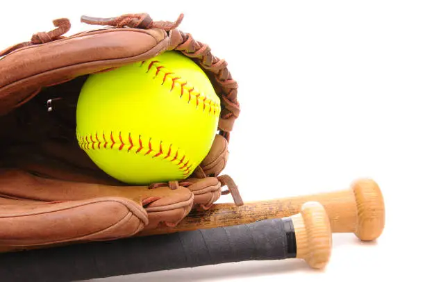 Closeup of a Softball Glove ball and two bats on white with copyspace. Horizontal format.