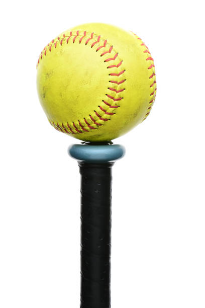 Softball on Knob of Bat A used yellow softball resting on the knob end of an aluminum bat. Vertical format isolated on white. sports bat stock pictures, royalty-free photos & images