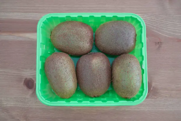 Photo of Five Kiwi fruits in a green box on wooden background