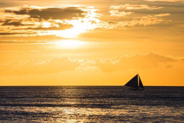 istock One outrigger sailboat on the horizon at sunset 953695802