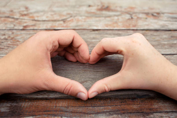 istock hands in the shape of hart on wooden background 953704852