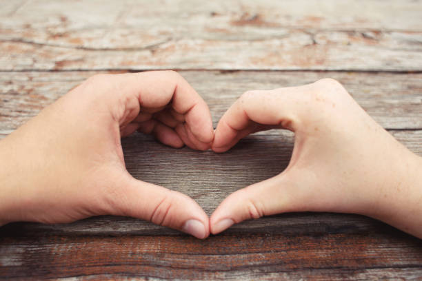 istock hands in the shape of hart on wooden background 953704862