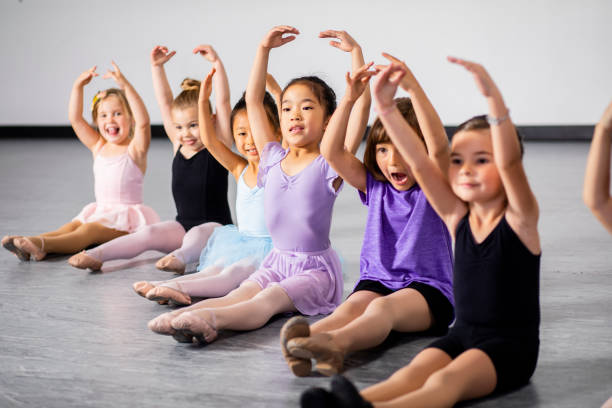 Row of Cute Young Diverse Students in Ballet Dance Class A diverse group of students practicing in dance class dancing school stock pictures, royalty-free photos & images