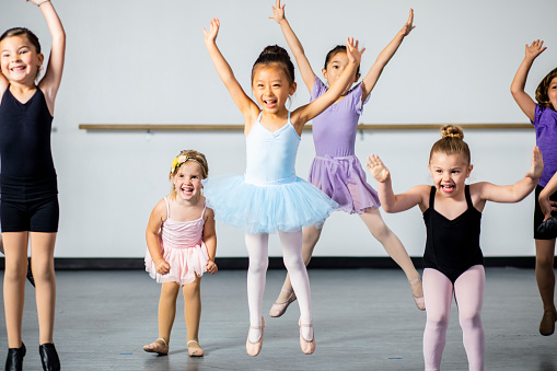 A diverse young group of students practice in musical theatre and ballet combo dance class
