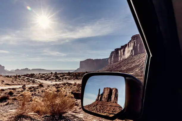 Stock photo of the Mittens in a side view car mirror at Sunrise in the beautiful Monument Valley National Park.